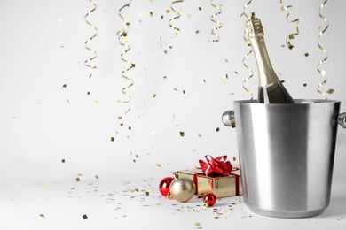 Happy New Year! Bottle of sparkling wine in bucket, gift box and festive decor on white background, space for text