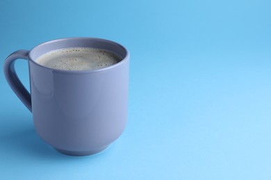 Mug of freshly brewed hot coffee on light blue background, space for text
