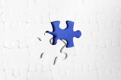 Blank white puzzle with separated piece on blue background, top view