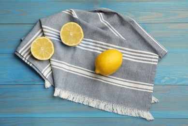Striped kitchen towel and lemons on light blue wooden table, flat lay