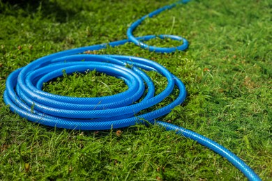Photo of Blue watering hose on green grass outdoors