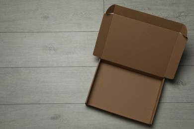 Photo of Empty open cardboard box on floor, top view. Space for text