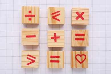 Photo of Wooden cubes with mathematical symbols and heart on sheet of grid paper, flat lay