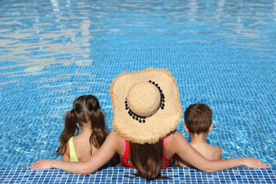 Woman with her children in swimming pool, back view. Summer vacation