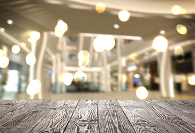 Empty wooden surface and blurred view of shopping mall. Space for design