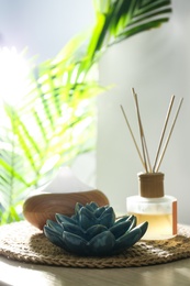 Aroma oil diffuser and reed air freshener on table in room