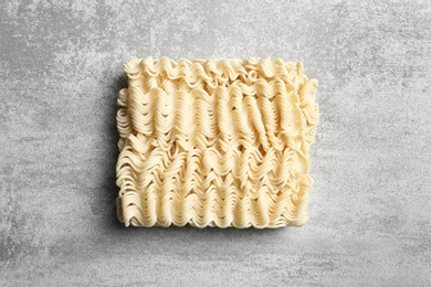 Block of quick cooking noodles on color background, top view