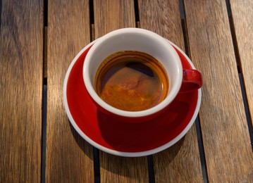 Cup of aromatic hot coffee on wooden table, above view