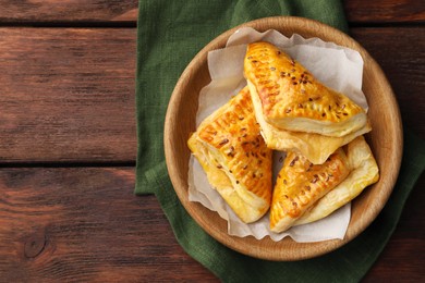 Photo of Fresh delicious puff pastry with cheese in bowl on wooden table, top view. Space for text