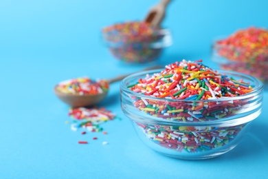 Colorful sprinkles in bowl on light blue background, closeup with space for text. Confectionery decor