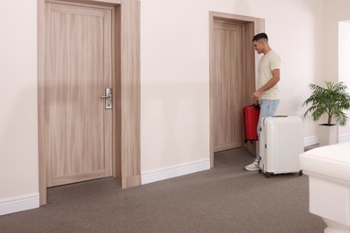 Happy man with suitcases in hotel corridor
