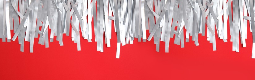 Silver tinsel on red background, top view. Banner design