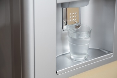 Modern cooler with glass of water, closeup