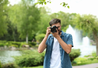 Photographer taking photo with professional camera in park