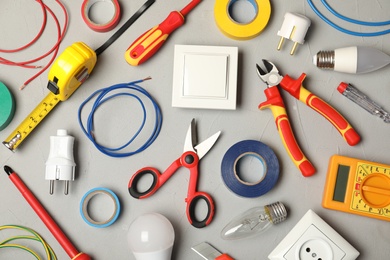 Flat lay composition with electrician's tools on gray background