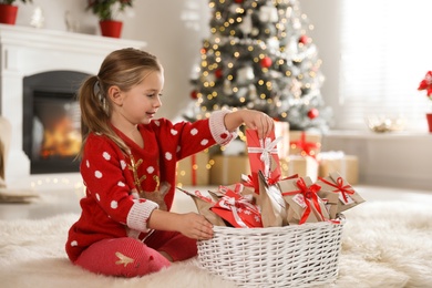Photo of Cute little girl taking gift from Christmas advent calendar at home