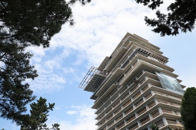 Photo of Multistory building under construction against cloudy sky, low angle view