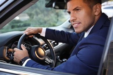 Handsome man driving his modern car, view from outside