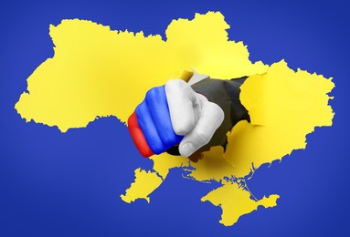 Image of Russian aggression against Ukraine. Man breaking through map of Ukraine with fist painted in colors of Russian flag