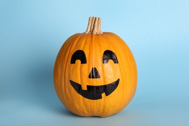 Pumpkin with drawn spooky face on light blue background. Halloween celebration