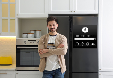 Young man near smart refrigerator in kitchen