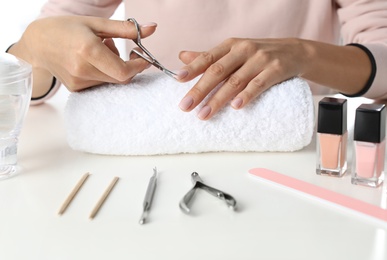 Woman cutting nails at table, closeup. At-home manicure