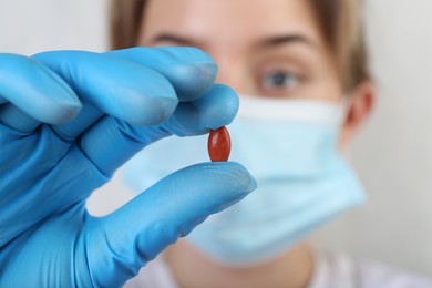 Doctor holding red pill, focus on drug. Anemia concept