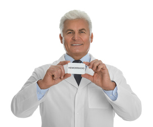 Doctor holding business card with word HEMORRHOID on white background