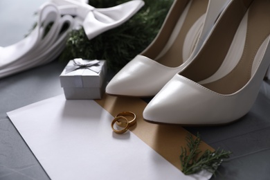 Composition with wedding rings, white high heel shoes and decor on grey background