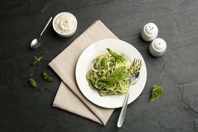 Delicious zucchini pasta with basil served on black slate table, flat lay