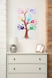 Family tree drawing with colorful palm prints on wall at home