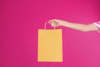Woman holding shopping bag on color background, closeup.  Mock-up for design