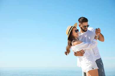 Happy young couple dancing at beach near sea. Honeymoon trip