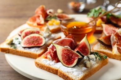 Sandwiches with figs, proscuitto and cheese on wooden table, closeup