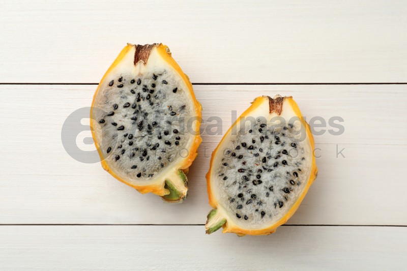 Photo of Delicious cut dragon fruit (pitahaya) on white wooden table, flat lay