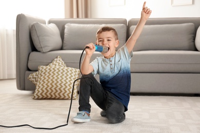 Cute funny boy with microphone in living room