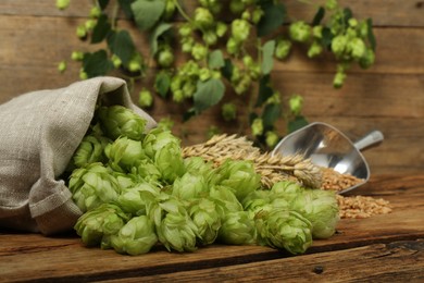 Photo of Fresh green hops, wheat grains and spikes on wooden table