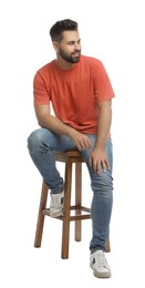 Handsome young man sitting on stool against white background