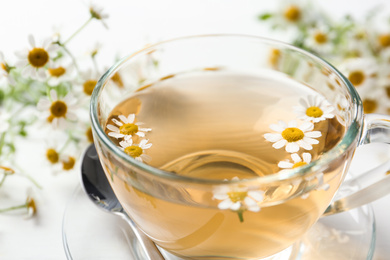 Fresh chamomile tea in cup on white table, closeup