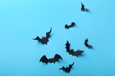 Paper bats on light blue background, flat lay. Halloween decor