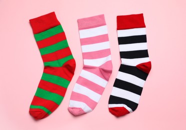 Different striped socks on light pink background, flat lay