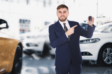 Image of Happy salesman with key in car salon