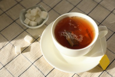 Photo of Tea bag in cup on table, closeup