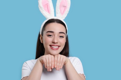 Photo of Happy woman wearing bunny ears headband on turquoise background, space for text. Easter celebration