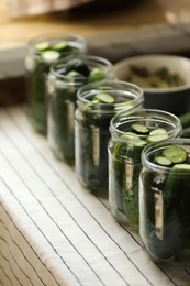 Set of glass jars with fresh cucumbers prepared for canning on table. Space for text