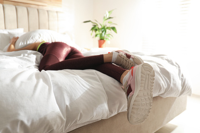 Lazy young woman sleeping on bed instead of morning training, focus on legs