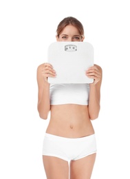 Photo of Happy slim woman satisfied with her diet results holding bathroom scales on white background