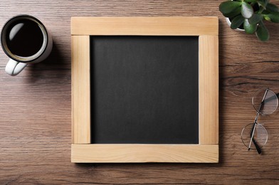 Clean small blackboard, coffee, chalk and glasses on wooden table, flat lay