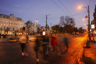 Photo of People crossing city street at evening, long exposure effect