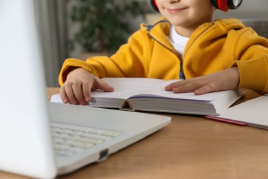 Cute little boy with modern laptop studying online at home, closeup. E-learning